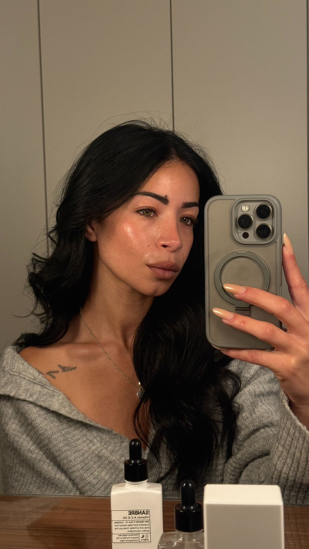 Woman holding a phone with skincare products on a table